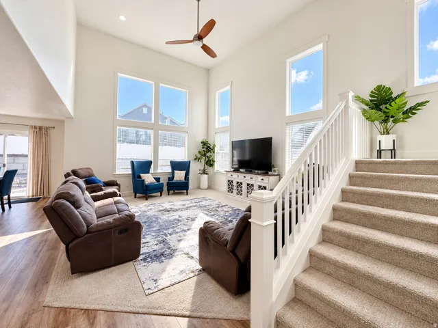 Vaulted ceiling with a wood-finish ceiling fan, wood-finish flooring, and a white staircase with carpeted treads