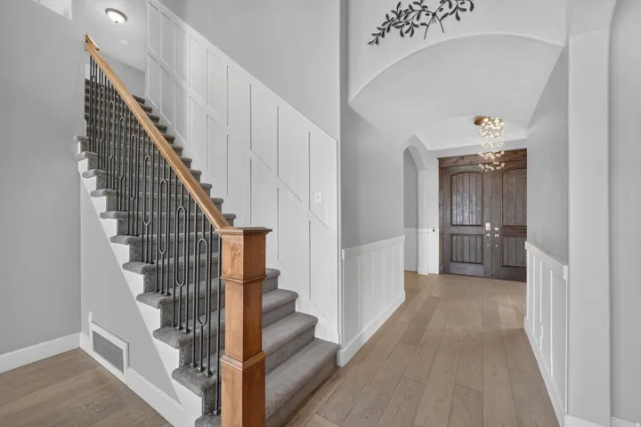 Sweeping staircase featuring carpeted treads, a wood handrail, and decorative metal balusters