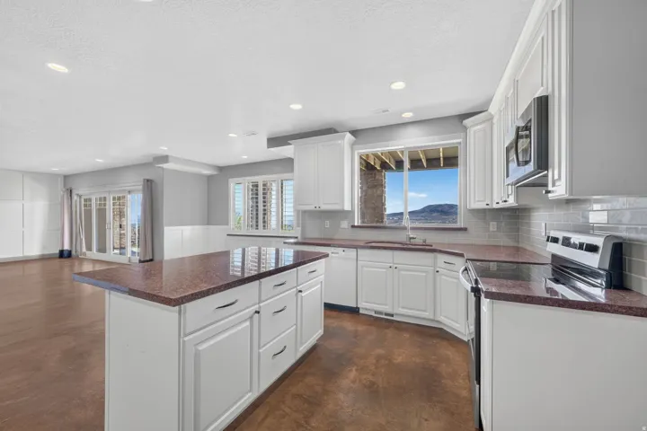 White cabinetry with dark countertops, stainless steel appliances, and a tiled backsplash