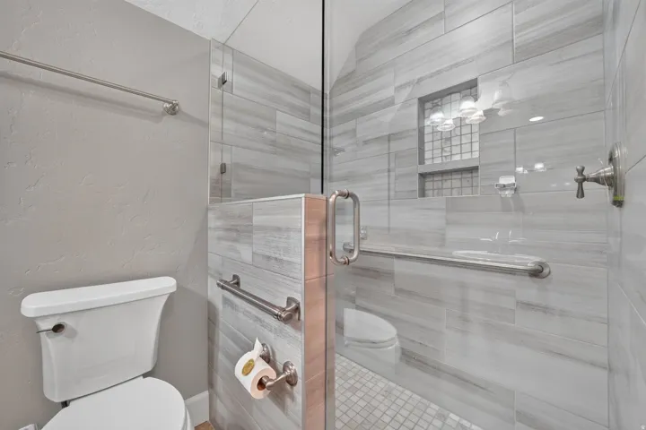 Enclosed shower with full-height tile surround, built-in recessed shelf, and glass shower enclosure