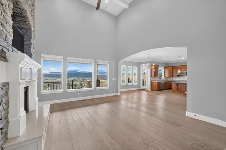 Expansive living area with vaulted ceilings, a stone-clad fireplace, and wood-finish flooring