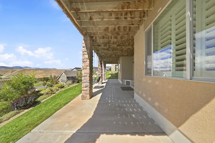 Covered patio area featuring stone-clad support columns and a textured stucco exterior