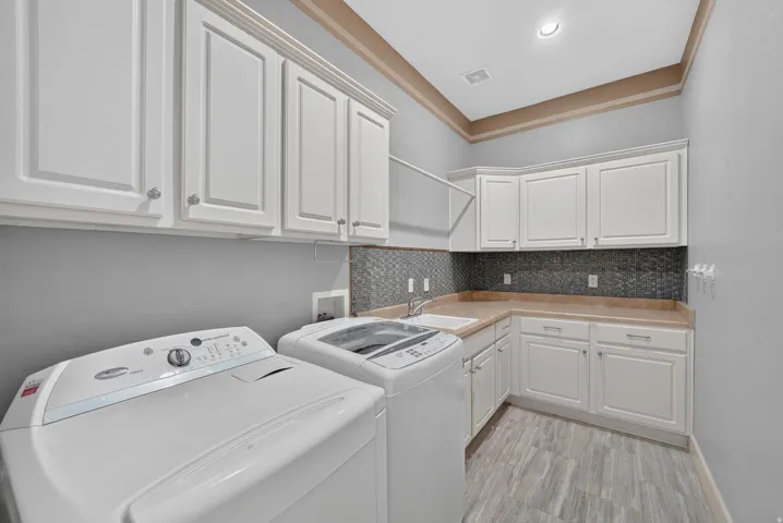 White shaker cabinetry, wood-finish flooring, undermount sink, mosaic tile backsplash, and recessed lighting