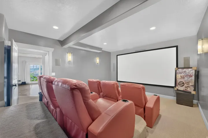 Home theater with a large projection screen, recessed lighting, and wall-mounted sconces