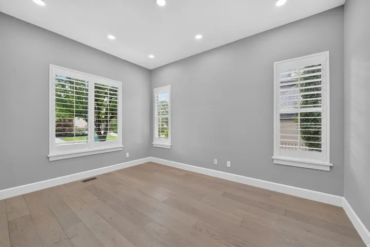Recessed ceiling lighting, multiple windows with plantation shutters, light wood-finish flooring, and crisp white trim