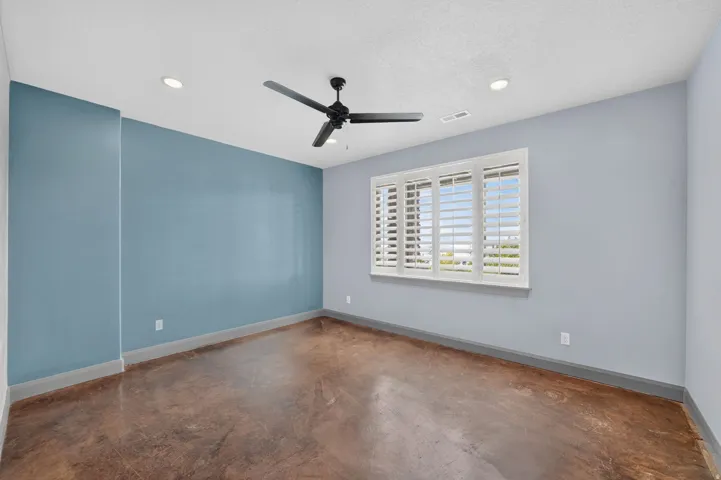 Recessed lighting, ceiling fan, window with plantation shutters, and stained concrete flooring