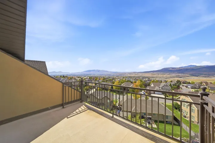 Balcony with a metal railing and a stucco exterior, offering expansive long-range scenery featuring mountains and distant water