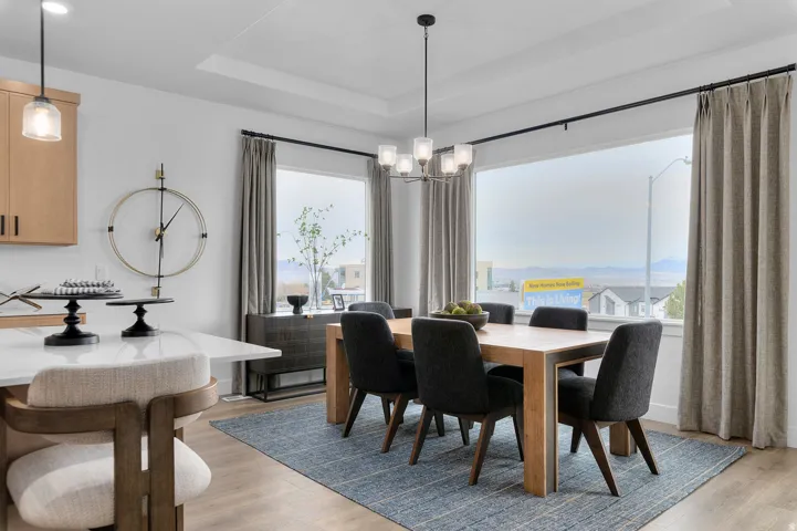 Recessed ceiling lighting, tray ceiling, wood-finish flooring, large picture windows, and pendant lighting