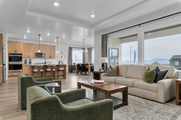 Open-concept living area with wood-finish flooring, a tray ceiling, and recessed lighting