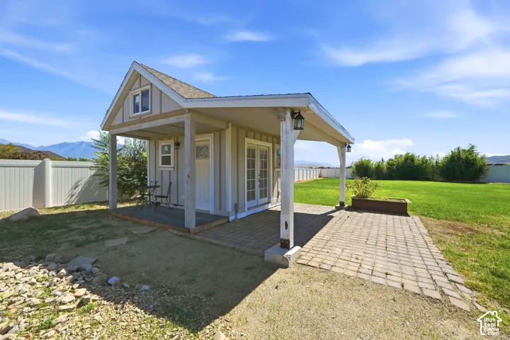 A-frame structure featuring a covered porch, brick paver patio, double French doors, and an upper-level window