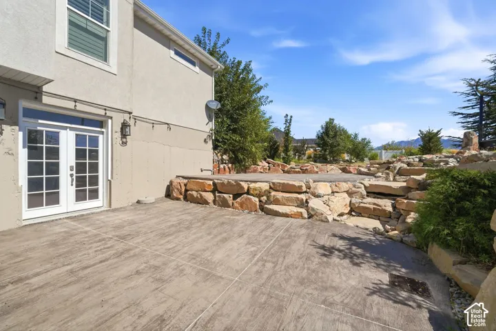 Stucco exterior with a double French door entry, leading to an expansive stamped concrete patio