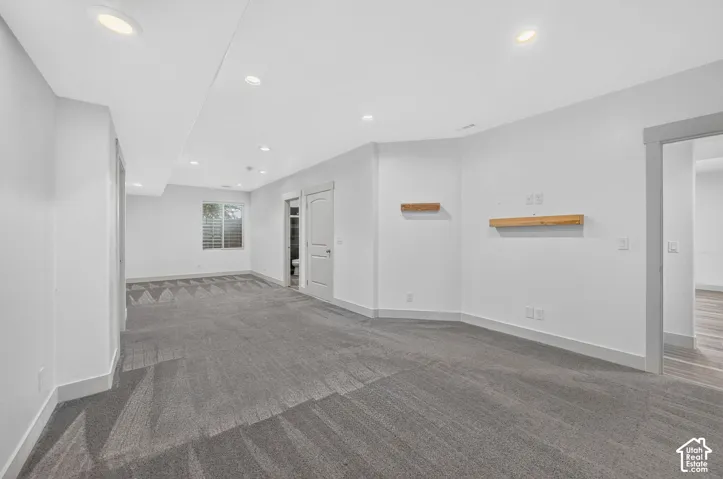 Recessed lighting illuminates the carpeted flooring and white walls