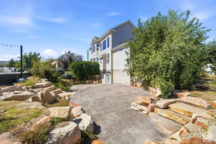 Multi-level landscaping featuring natural rock elements and mature greenery, with a concrete pathway