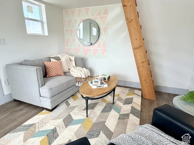 Wood-finish flooring, accent wall with geometric pattern, built-in wooden ladder, and a window for natural light