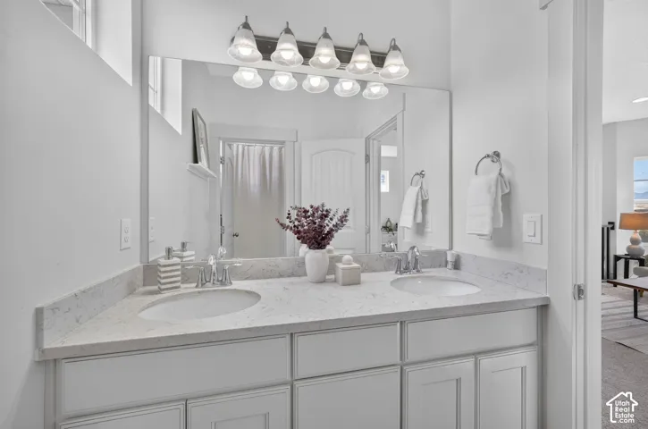 Dual vanity featuring undermount sinks, chrome faucets, and stone-finish countertops