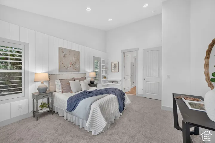 Textured wall paneling, plantation shutters, recessed lighting, arched doorways, and light grey carpeting