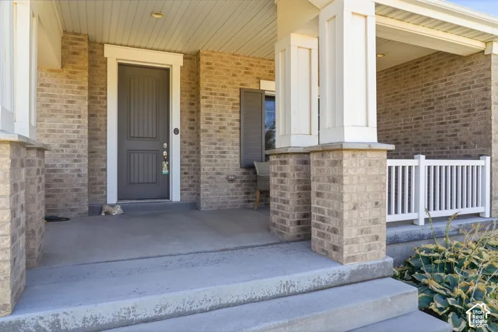 Brick exterior with a covered porch, concrete steps, and a panel-style entry door