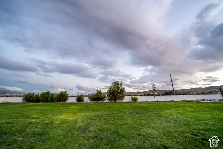 Expansive green lawn with a white privacy fence and mature landscaping