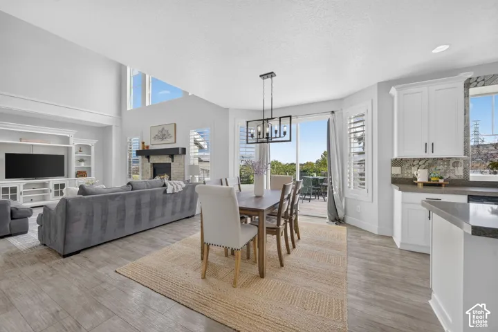 Vaulted ceiling with transom windows, wood-finish flooring, built-in media center, stone-clad fireplace with mantel, and a sliding glass door to the exterior