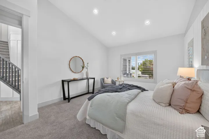 Vaulted ceiling, recessed lighting, carpet flooring, window with plantation shutters, and board and batten wall accent