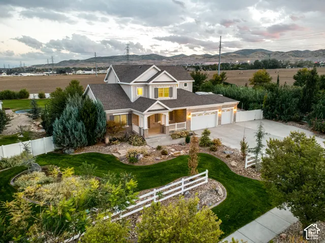 Property exterior featuring a multi-car garage, concrete driveway, and expansive lawn with mature landscaping