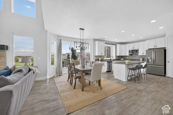 Expansive open concept living area featuring vaulted ceilings, wood-finish flooring, and a modern kitchen with a center island and stainless steel appliances