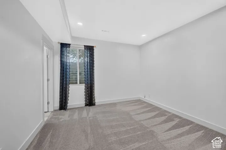 Recessed ceiling lighting, tray ceiling, neutral wall tones, window with blinds, and patterned carpeting