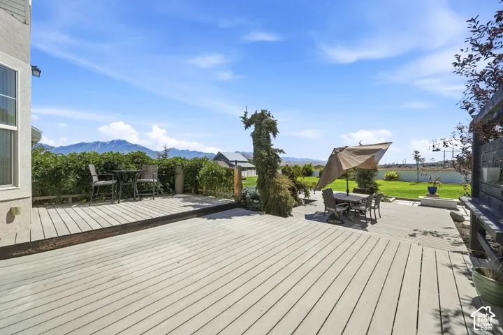 Expansive composite deck, mature perimeter landscaping, and mountain backdrop
