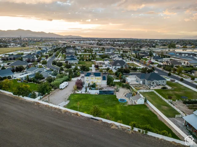 Expansive residential property featuring multiple structures, a substantial grassy yard, and a white picket fence, all within a neighborhood setting with distant mountains