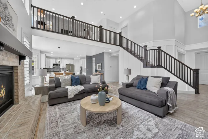 Two-story living area with high ceilings, a brick-surround fireplace, and wood-finish flooring