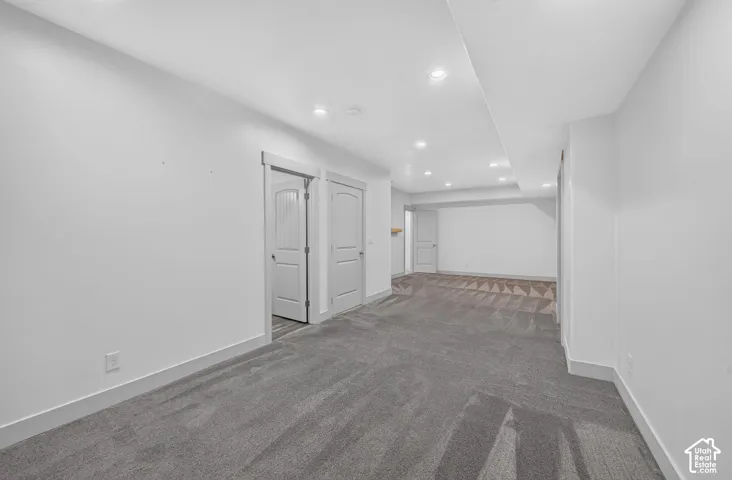Recessed lighting illuminates the open area with gray patterned carpeting