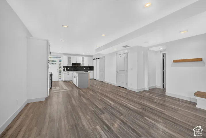 Open-concept kitchen with white cabinetry and dark backsplash