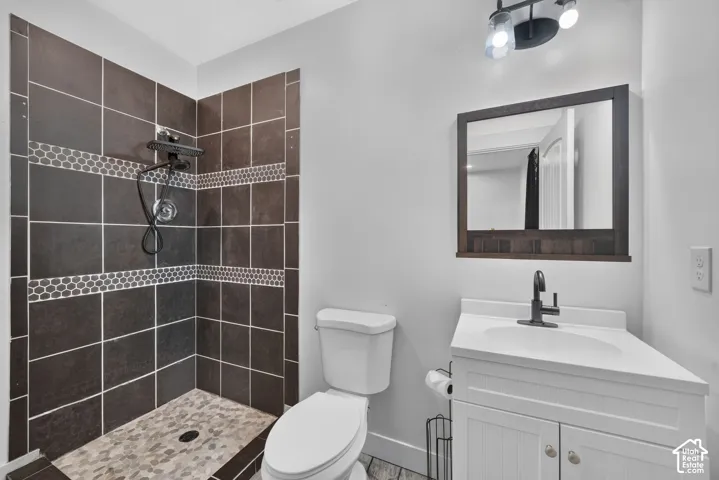 Walk-in shower with dark square tiles and mosaic accent bands
