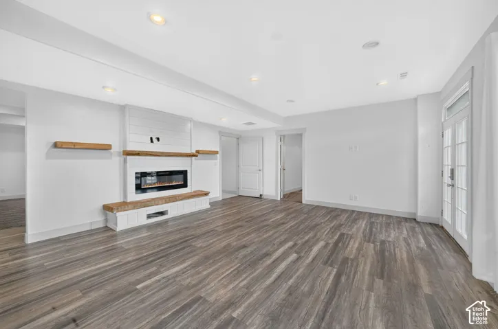 Spacious room featuring wood-finish flooring, recessed lighting, and white walls