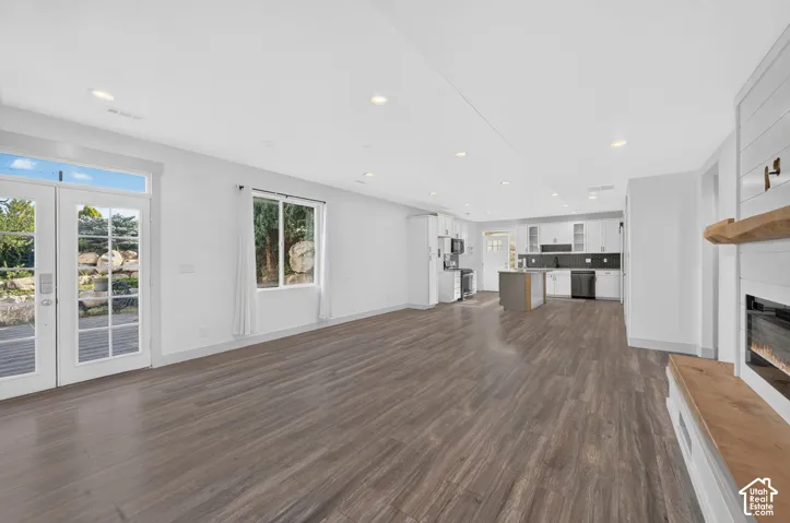 Open-concept living space featuring wood-finish flooring, recessed lighting, and a modern fireplace with a wood mantel