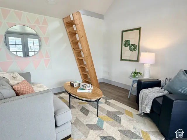 Slanted wooden ladder, wood-finish flooring, white walls, recessed ceiling lighting, and a painted geometric accent wall