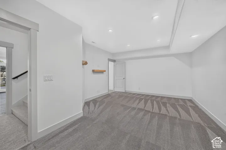 Spacious room featuring patterned carpet flooring, recessed lighting, and a built-in wall shelf