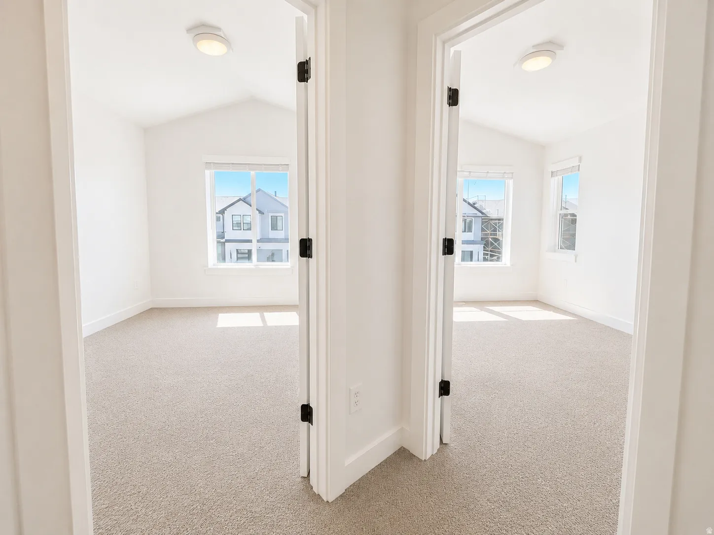 Vaulted ceilings with flush-mount lighting, neutral carpeting, and white trim