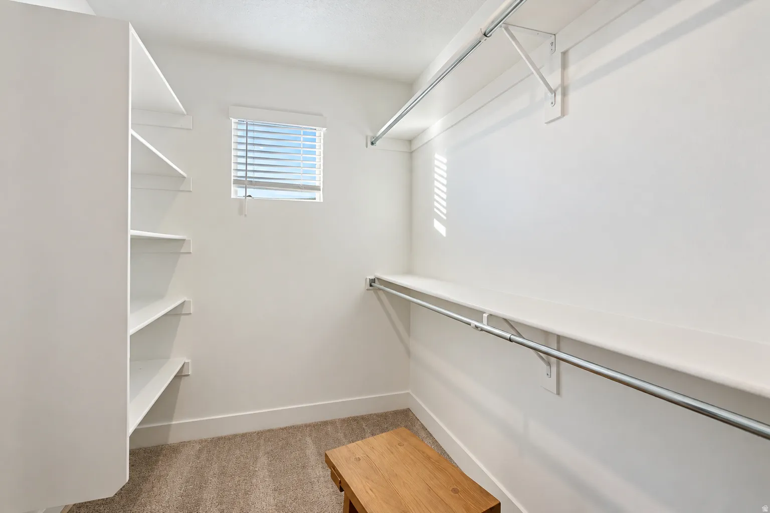 Built-in shelving, hanging rods, and a window with blinds