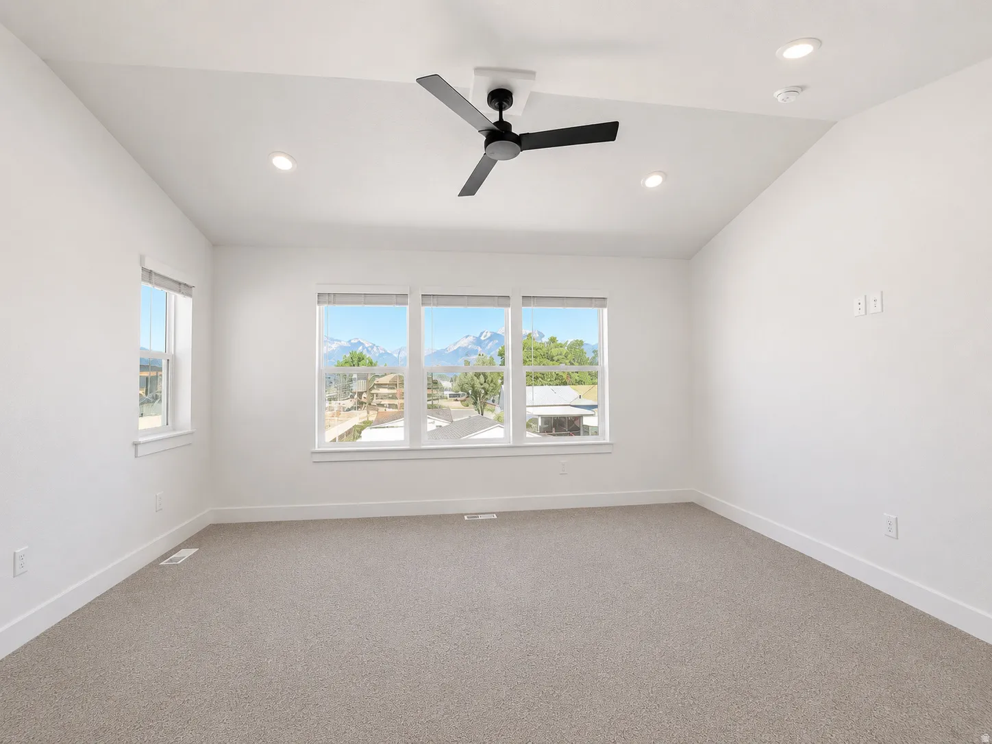 Vaulted ceiling with a contemporary ceiling fan, recessed lighting, expansive windows, and plush carpet flooring