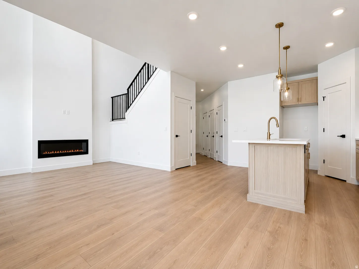 Open-concept living space with wood-finish flooring, a contemporary linear fireplace, and recessed lighting