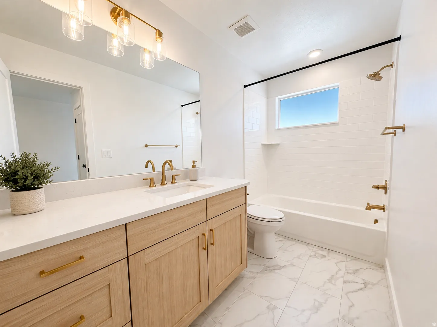 Light wood-finish vanity with gold-tone hardware and white countertop