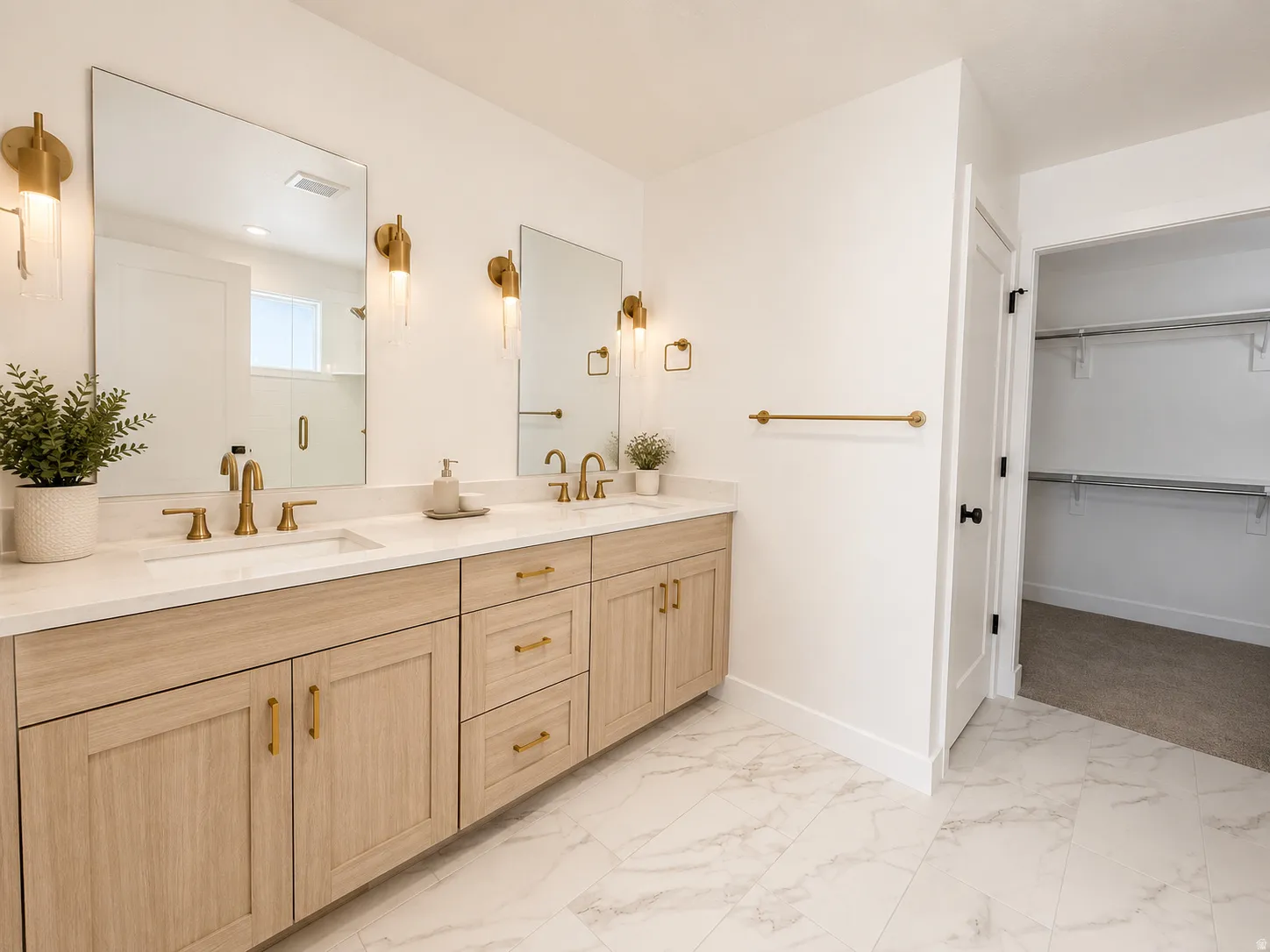 Dual vanity with light wood-finish cabinetry, white countertop, and gold-finish fixtures