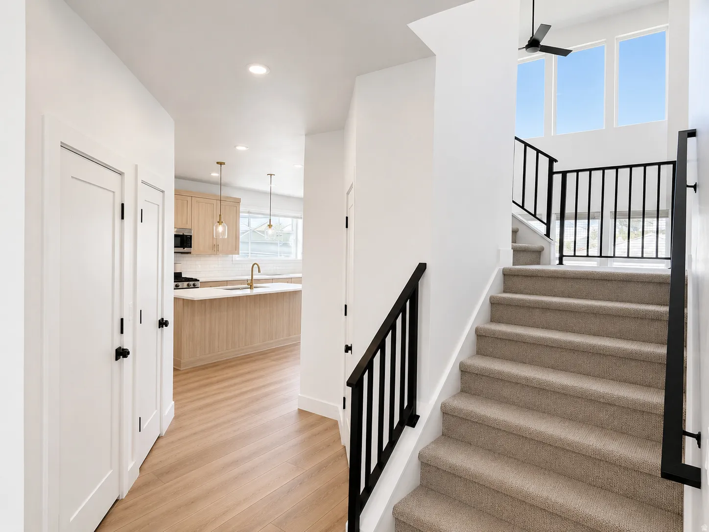 Wood-finish flooring throughout, with a carpeted staircase featuring black metal railings