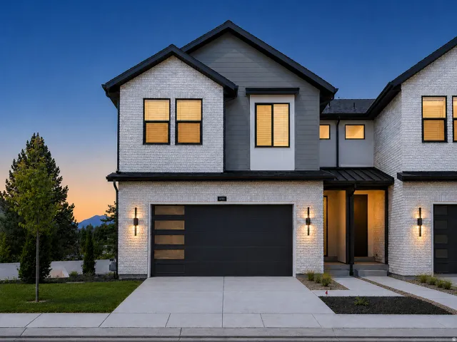 Modern architectural design with a gabled roofline and a dark panel garage door
