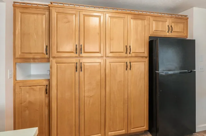 Extensive light wood cabinetry with dark hardware and a built-in black refrigerator