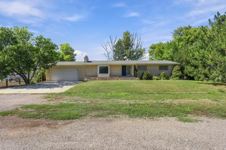 Single-story residence with an attached garage, front lawn, and mature trees
