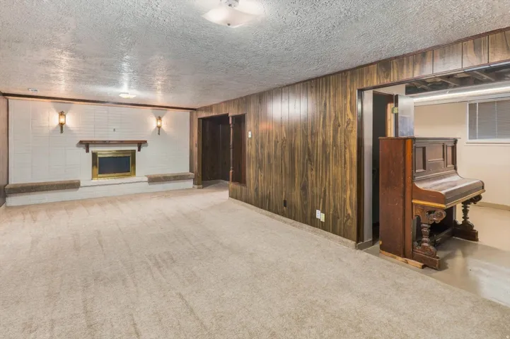 Carpeted room with a central fireplace, white tiled surround, and wood mantel