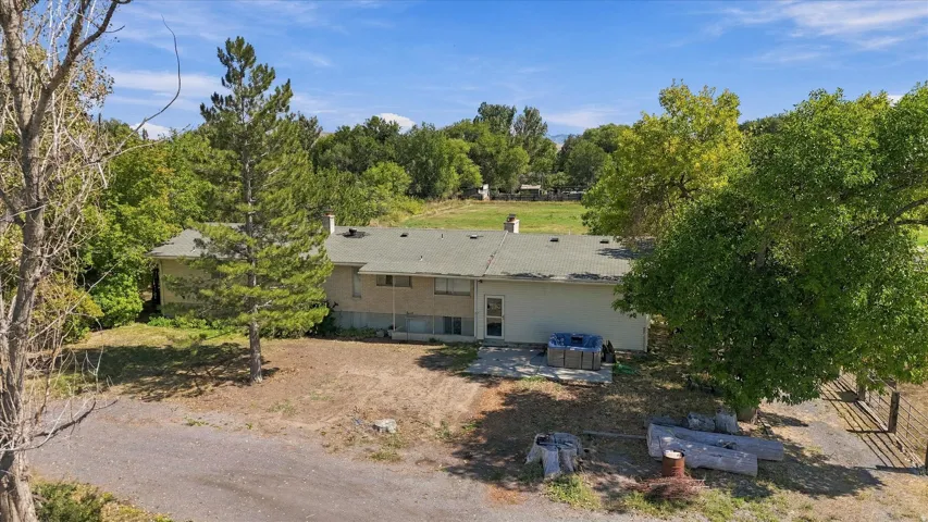 Expansive property featuring a gravel driveway, mature trees, and a stone patio