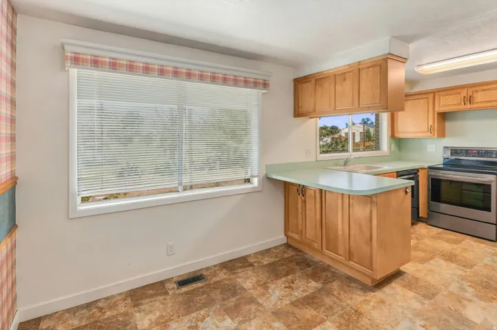 Kitchen featuring wood cabinetry, stainless steel range, light green countertops, and patterned floor tile